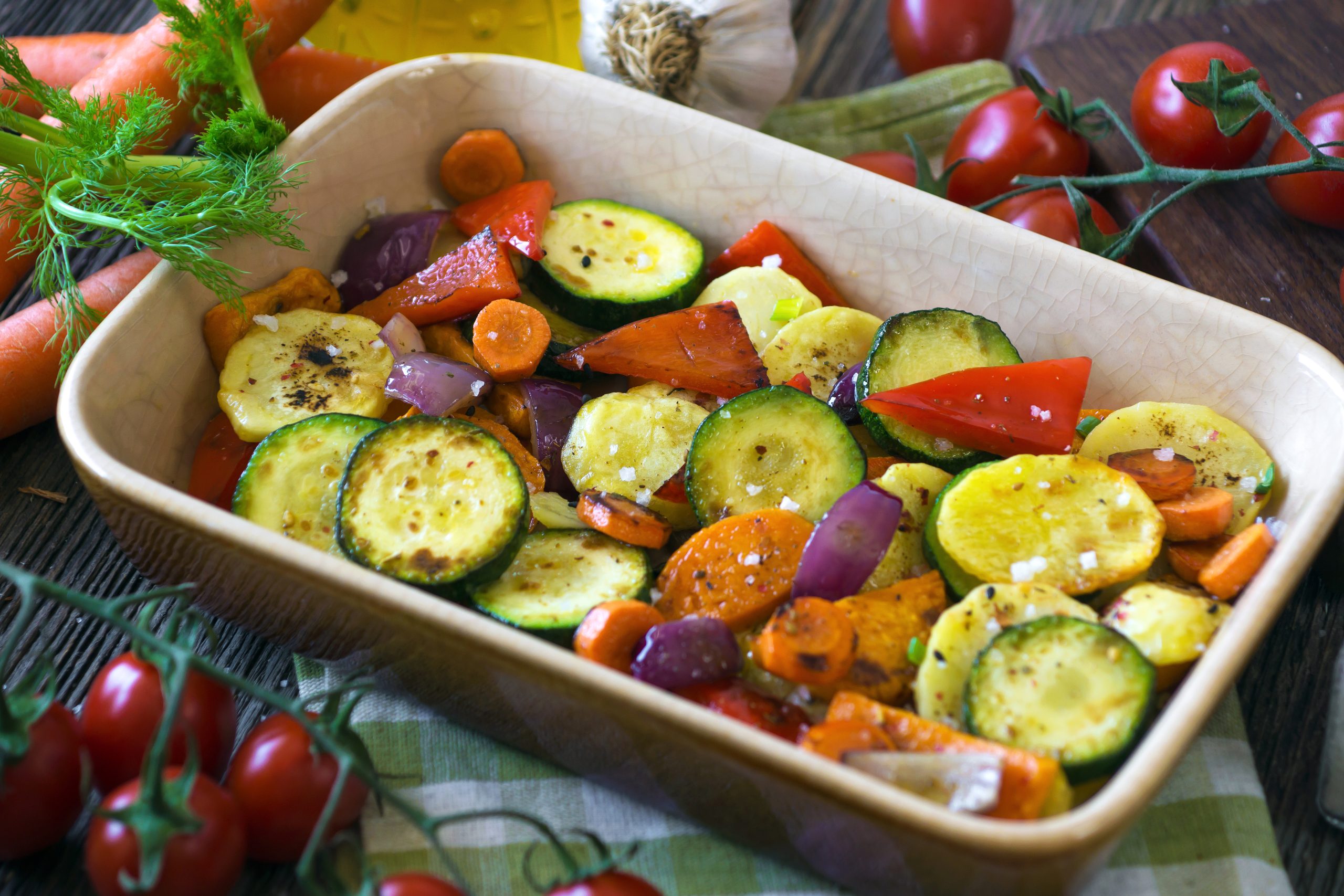 Roasted vegetables with olive oil on wooden background